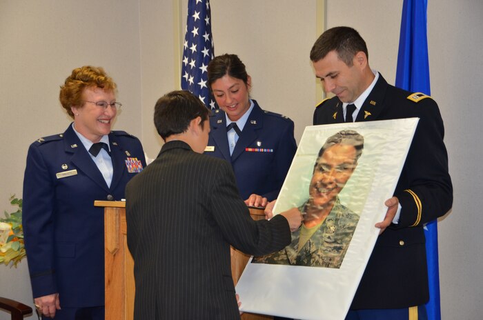 Daniel, son of Maj. Monica Lovasc, pins the rank of lieutenant colonel on a poster board of his mother during a promotion ceremony May 21 at the Joint Base Charleston Airman and Family Readiness Center. Lovasz, who is currently deployed with the 387th Air Expeditionary Group at Camp Buehring, Kuwait, was able to share this moment with her family back home through video chat. (U.S. Air Force photo/Senior Airman Anthony J. Hyatt)