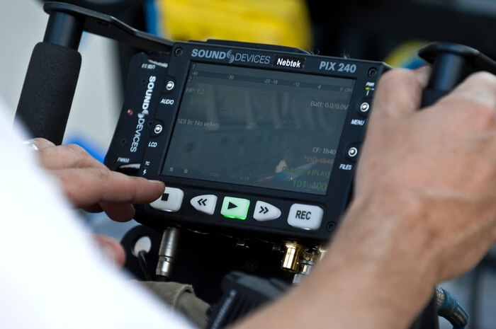 A camera operator from Gurasich Spence Darilek and McClure advertising agency adjusts a handheld video recorder monitoring a remote camera while filming May 15, 2012, at Nellis Air Force Base, Nev. Nellis Air Force Base, the Air Force Recruiting Service and Randolf Air Force Base, coordinated to help produce the newest Air Force recruiting tool, “Rapid Strike.” (U.S. Photo by Senior Airman Jack Sanders)
