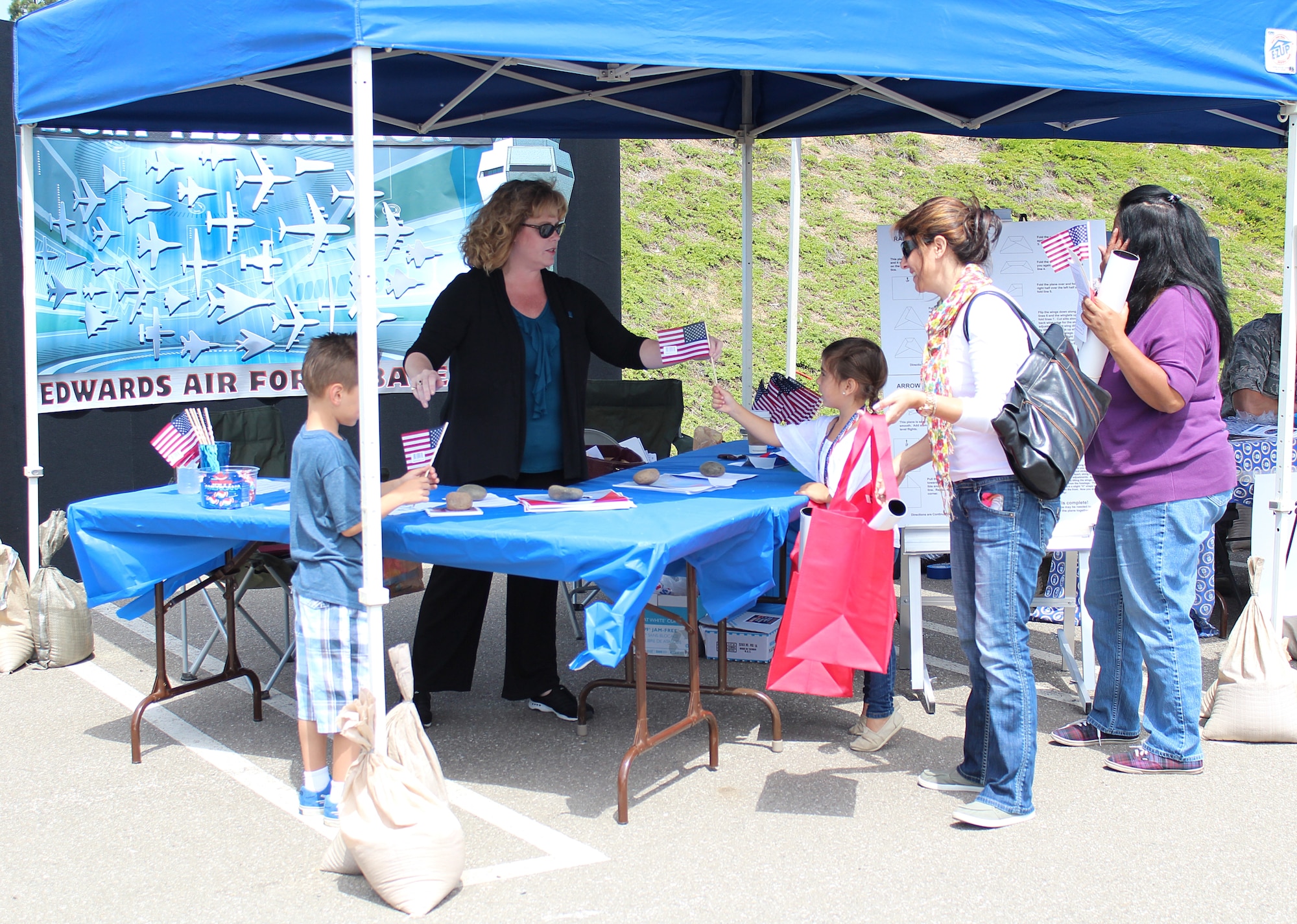 Elizabeth Doss, 95th Air Base Wing Public Affairs director, hands out flags, information about the base, and paper planes to passersby.  The Community Relations section of 95th ABW PA set up a booth for the three-day Torrance Armed Forces Day Celebration. (U.S. Air Force photo by Melissa Buchanan)