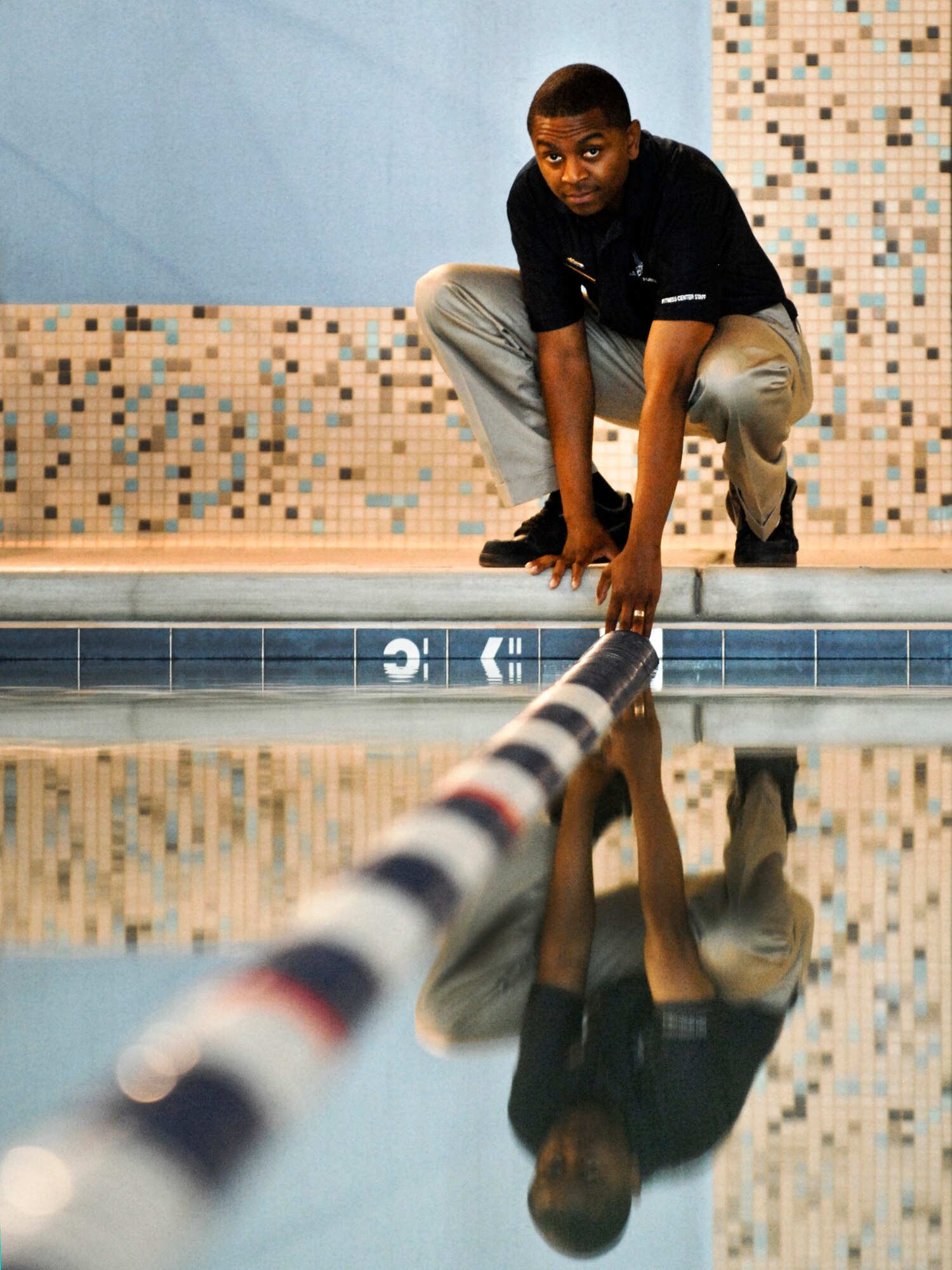 U.S. Air Force Staff Sgt. Jeffrey Cook, 99th Force Support Squadron specialist, adjusts a guide rope in the Nellis Air Force Base Gym pool Mar. 17, 2012. The base pool uses energy from solar panels to heat the water helping to keep the building energy efficient. (U.S. Air Force photo by Senior Airman Jack Sanders)