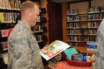 Col. Scott Peel, 902nd Mission Support Group commander, examines an activity package May 18 at the Joint Base San Antonio-Randolph library for the kick off of the summer reading program.  (U.S. Air Force photo/Rich McFadden) 