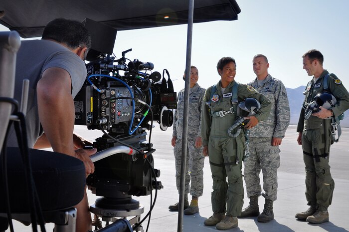 Senior Airman Jody Aguilar, Raptor Aircraft Maintenance Unit F-22 avionics specialist, Maj. Shawna Kimbrell, 6th Combat Training Squadron assistant director of operations, Senior Airman Andrew Zehm, Raptor Aircraft Maintenance Unit F-22 dedicated crew chief, and Maj. Paul Jelinek, 57th Wing commander's action group member share a laugh as they wait for a camera operator to make adjustments to his camera shot May 19, 2012 at Nellis Air Force Base, Nev. The four Airmen will appear in the Air Force Recruiting Service's new simulator ride set for a September debut at large public events around the world. (Air Force Photo by 1st Lt. Ken Lustig, Released)