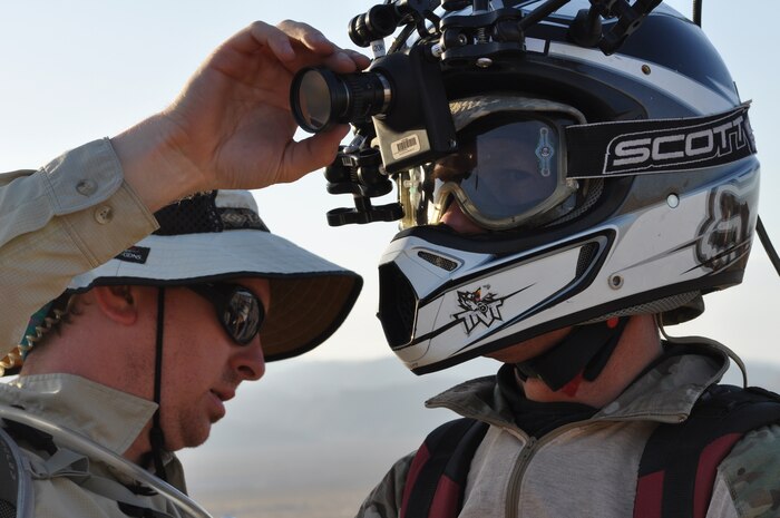 Stunt performer Devin Blackwell consults with Andrews Yarborough on orientation of a mounted hi-resolution camera for a desert dirt biking scene filmed for the Air Force Recruiting Service May 17, 2012, at Nellis Air Force Base, Nev. The stunt performer was following USAF Combat Control Team members as they simulated a reconnaissance mission in hostile territory for use in a recruiting service film shot over the course of six days and involving several Nellis-based units. The film will be released in the Fall as part of an Air Force Recruiting Service interactive ride explaining the mission of the Air Force. (U.S. Air Force photo by Benjamin Newell, Released)