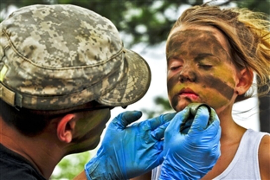 A soldier transforms 7-year-old Kayiah into a camouflaged Army Ranger at the 6th Ranger Training Battalion’s annual open house on Eglin Air Force Base, Fla., May 12, 2012. The event enabled the public to learn how Rangers train and operate, showing dive equipment, weapons, a reptile zoo and zodiac boats.