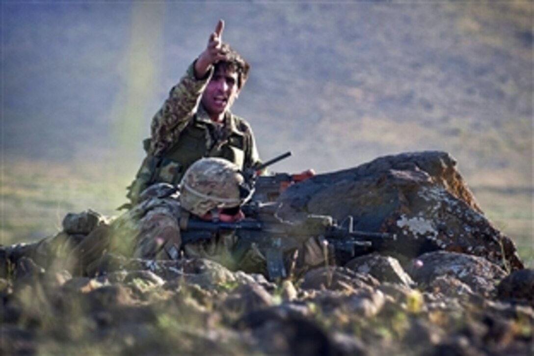 An Afghan soldier directs fellow soldiers during a firefight near Combat Outpost Giro while a U.S. Army paratrooper fires on insurgent positions in Afghanistan's Ghazni province, May 17, 2012.