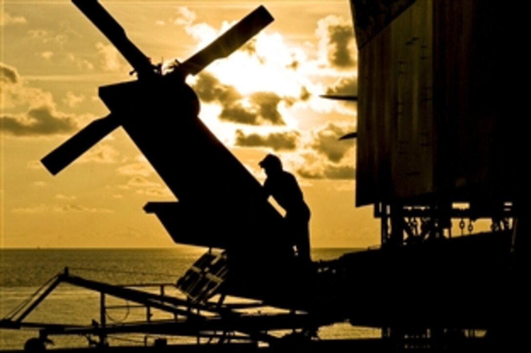 A U.S. Navy sailor performs maintenance checks before evening helicopter operations on the flight deck aboard the U.S. 7th Fleet flagship USS Blue Ridge under way in the Java Sea, May 21, 2012. The sailor, an airman, is assigned to Helicopter Anti-submarine Squadron Light 51.