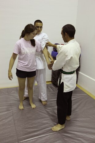 Kris W. Nelson (foreground), a Jiu-Jitsu student, shows Robin D. Jackson (left), the wife of Lance Cpl. Cassidy W. Jackson, a data network specialist with 8th Engineer Support Battalion, 2nd Marine Logistics group, the proper way to perform a defensive compliance technique during a self-defense class aboard Camp Lejeune, N.C., May 23, 2012.  The spouses who participated in the class had the opportunity to become skilled at multiple escaping techniques, take downs and pressure points, and practiced each individual move step-by-step with the guidance of former Jiu-Jitsu students.