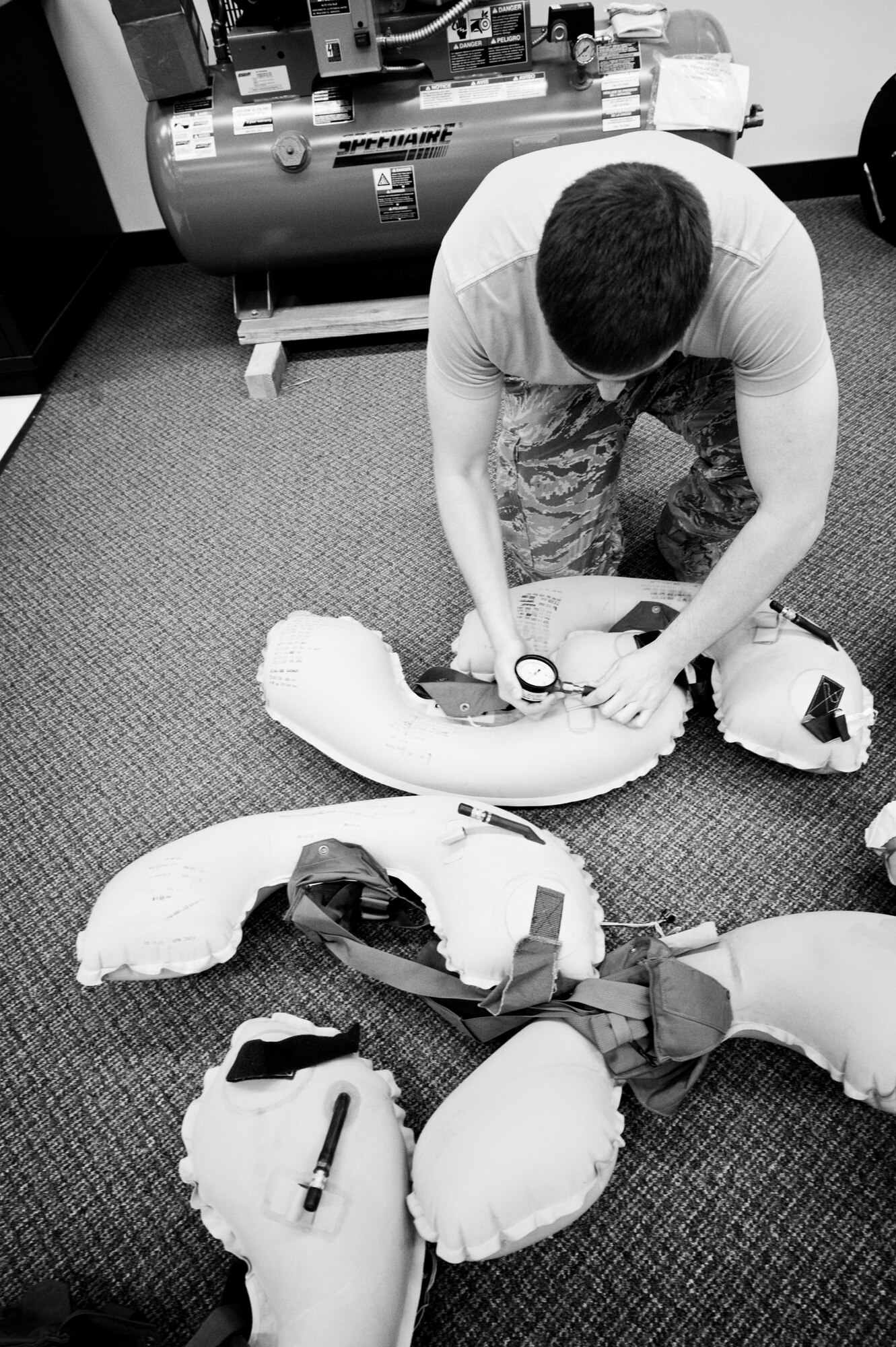 YOKOTA AIR BASE, Japan -- Airman 1st Class Colton Hughes, 374th Operations Support Squadron aircrew flight equipment apprentice, checks the air pressure in pounds per square inch in life preserver units after a six-hour leak test at Yokota Air Base, Japan, May 21, 2012. The life preserver units are filled with air to two pound per square inch and must not go below one and a half pounds per square inch after a six-hour leak test. (U.S. Air Force photo by Airman 1st Class Krystal M. Garrett)  