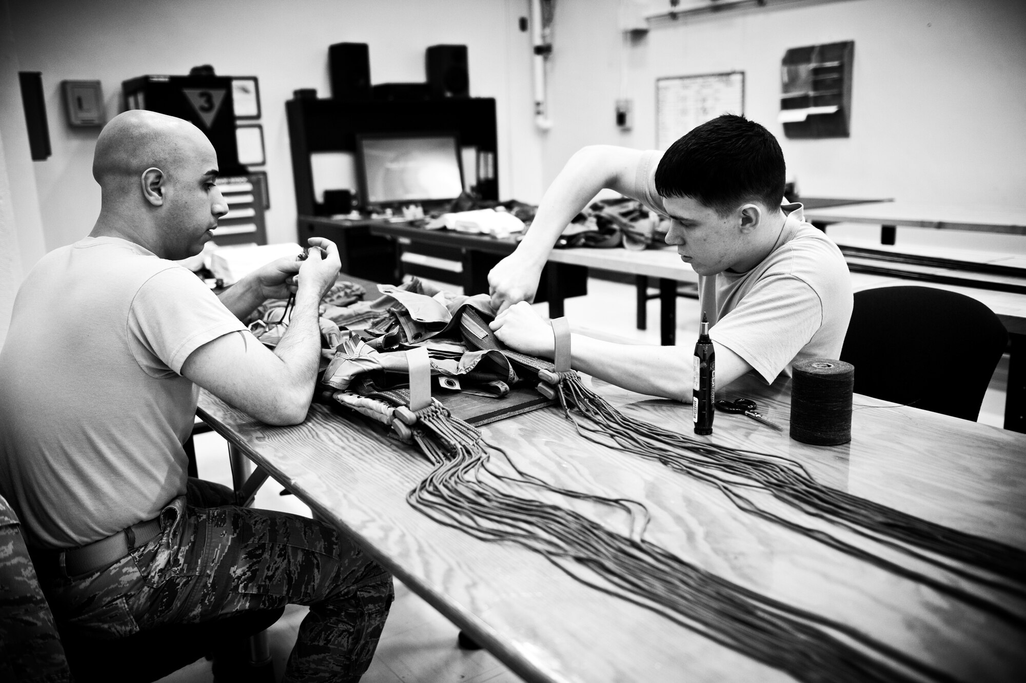 YOKOTA AIR BASE, Japan -- Senior Airman Phillip Rodriguez, left, and Senior Airman Aaron Hofner, 374th Operations Support Squadron aircrew flight equipment journeymen, repair a parachute at Yokota Air Base, Japan, May 12, 2012. Over time, the fabric in the parachutes can break down, requiring periodic maintenance. (U.S. Air Force photo by Airman 1st Class Krystal M. Garrett)