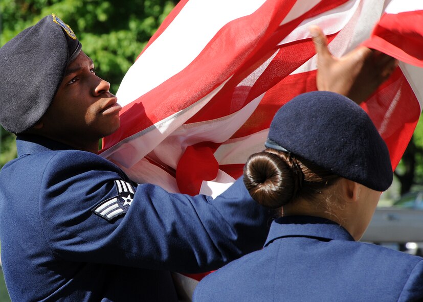 Senior Airman Christopher Hill retrieves the flag with the assitance from Airman 1st Class Kycia Montero, both 92nd Security Forces Squadron installation patrolmen, during the National Police Week remembrance retreat ceremony at Fairchild Air Force Base, Wash., May 15, 2012. Retreat serves as a two-fold purpose. It signals the end of the official duty day and it pays respect to the U.S. flag. (U.S. Air Force photo by Staff Sgt. Michael Means/Released)