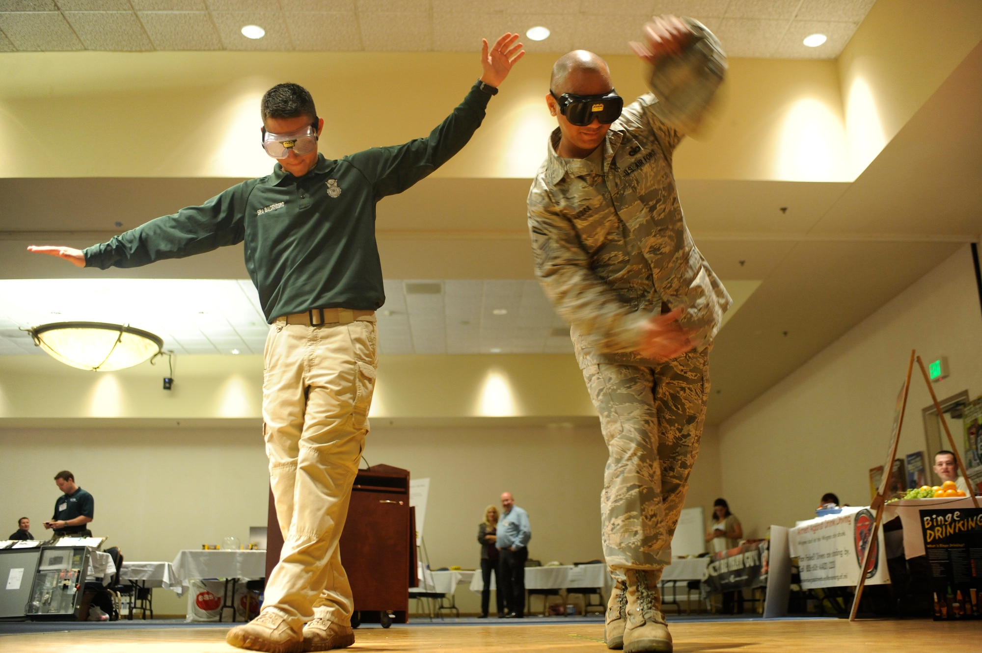 VANDENBERG AIR FORCE BASE, Calif. -- Senior Airman Zachary Baldenegro, 30th Security Forces Squadron conservation law enforcement officer, and Master Sgt. Bradford Cambra, 30th Space Wing Wing Staff Agencies and Comptroller Squadron first sergeant, walk a line using vision impaired goggles during a  safety expo at the Pacific Coast Club here Wednesday, May 23, 2012. Multiple organizations participated in the expo to show safety equipment and services they provide on and off base. (U.S. Air Force photo/Staff Sgt. Andrew Satran)  