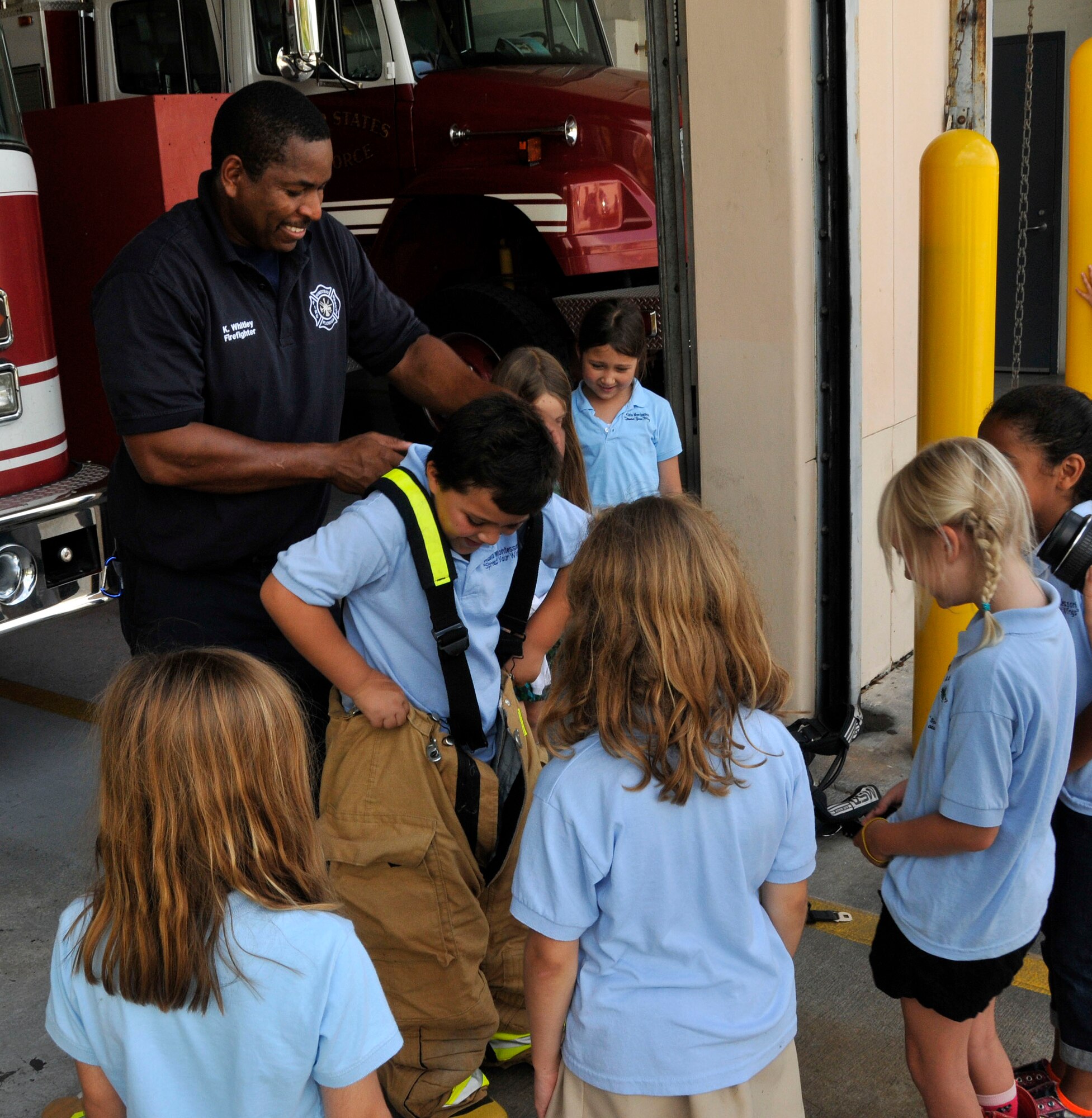Mr. Kevin Whitley, 482nd Fire Department, assists first and second-grade students from the Atala Montessori School for Creative Expression with donning a fire protectant suit at the base fire station during a tour of Homestead Air Reserve Base, May 18. (U.S. Air Force photo by Ross Tweten)