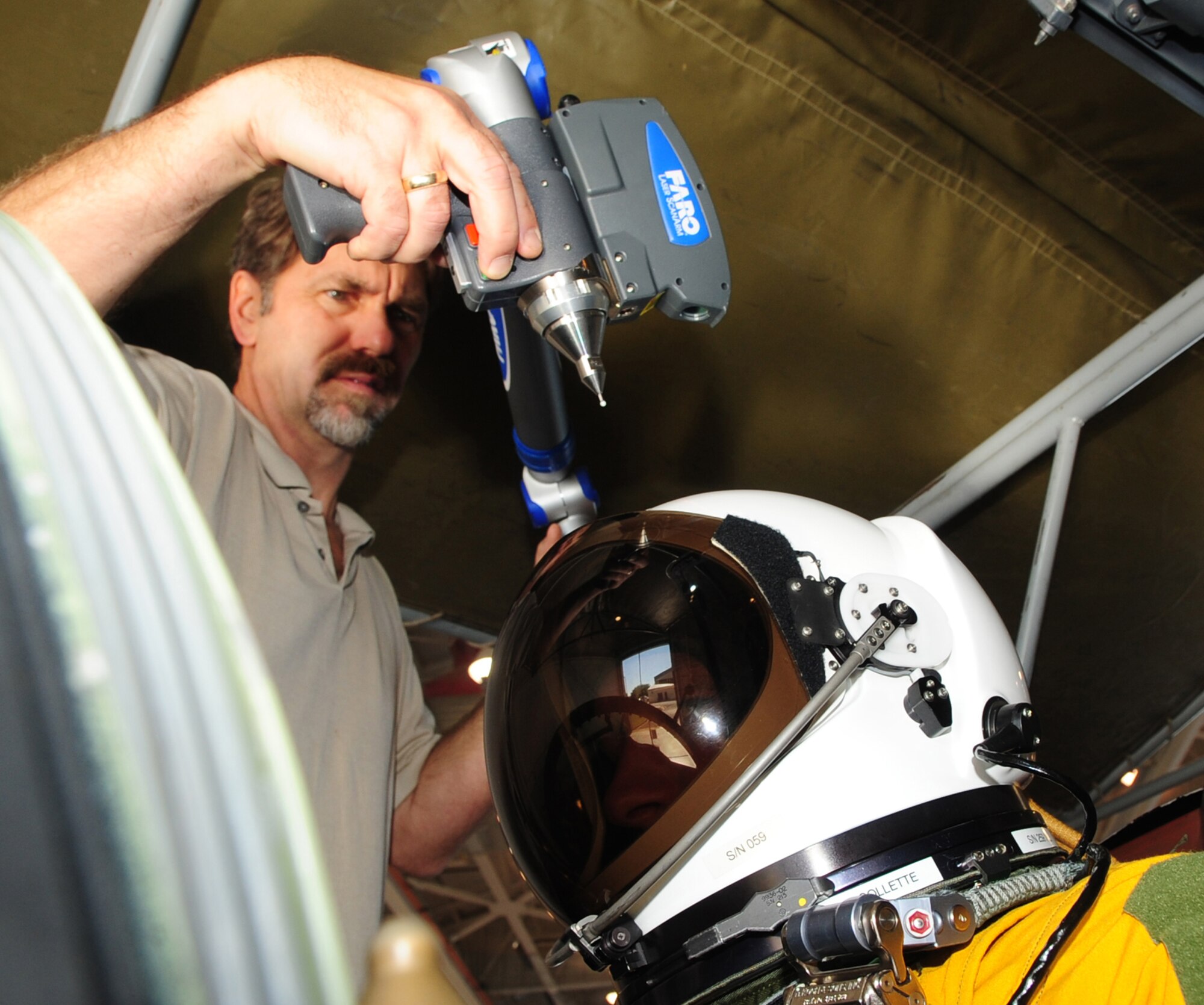 Dr. Jeffrey Hudson, InfoSciTex biological anthropologist working for 711th Human Performance Wing Wright-Patterson Air Force Base, Ohio, uses a coordinated measuring machine to map subject Airman 1st Class Alexander Scott, 9th Maintenance Squadron U-2 phase technician, inside a cockpit and create 3-D images to be used in pilot selection. Airmen from across base who fit the bill of too tall or too short to be pilots were used as test subjects. (U.S. Air Force photo by Senior Airman Shawn Nickel)