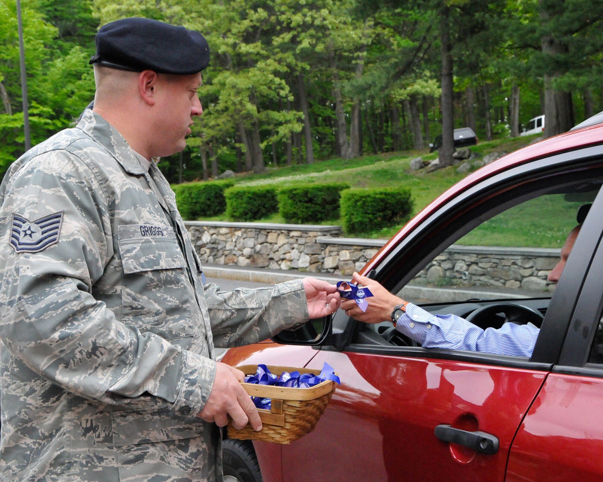 HANSCOM AIR FORCE BASE, Mass.—Tech. Sgt. Wayne Griggs, 66th Security Forces Squadron operations NCO in charge, distributes police week blue ribbons at the Hartwell Gate to employees arriving to work May 14. The ribbons honor officers who have lost their lives in the line of duty. (U.S. Air Force photo by Linda LaBonte Britt) 