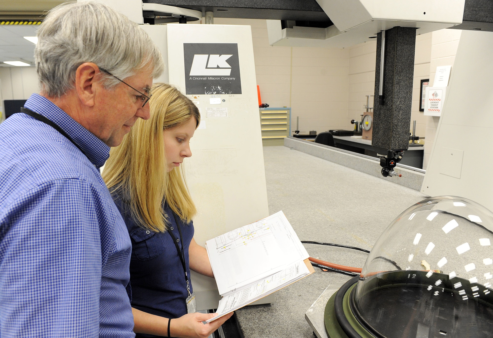 Gary Strandburg (left), a mechanical engineer in the 802nd Maintenance Support Squadron, and Kayla Brown, a C-130 structural engineer in the Aerospace Sustainment Directorate, consult on dimensional analysis and test plans for a C-130 Rear Vision Device. (U.S. Air Force photo by Tommie Horton)