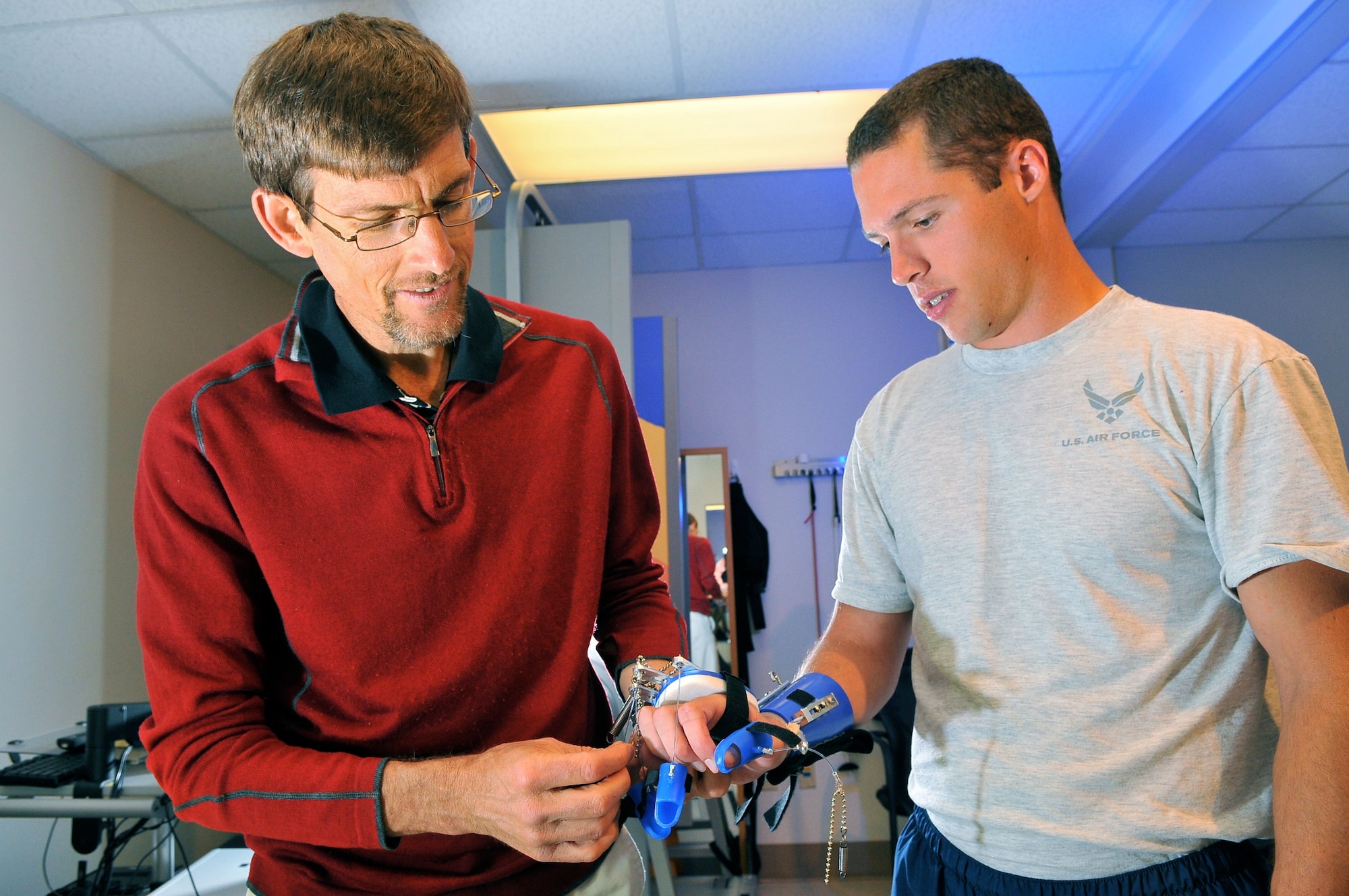 Chris Gillis, a physical therapist at San Antonio Military Medical Center, located in San Antonio helps Senior Airman Jayson Phillips remove a hand brace after a round of physical therapy. The brace helps Phillips open and close his hand while exercising. Phillips is currently recovering from a stroke he suffered Sept. 19, 2011. (U.S. Air Force photo/William Belcher)
