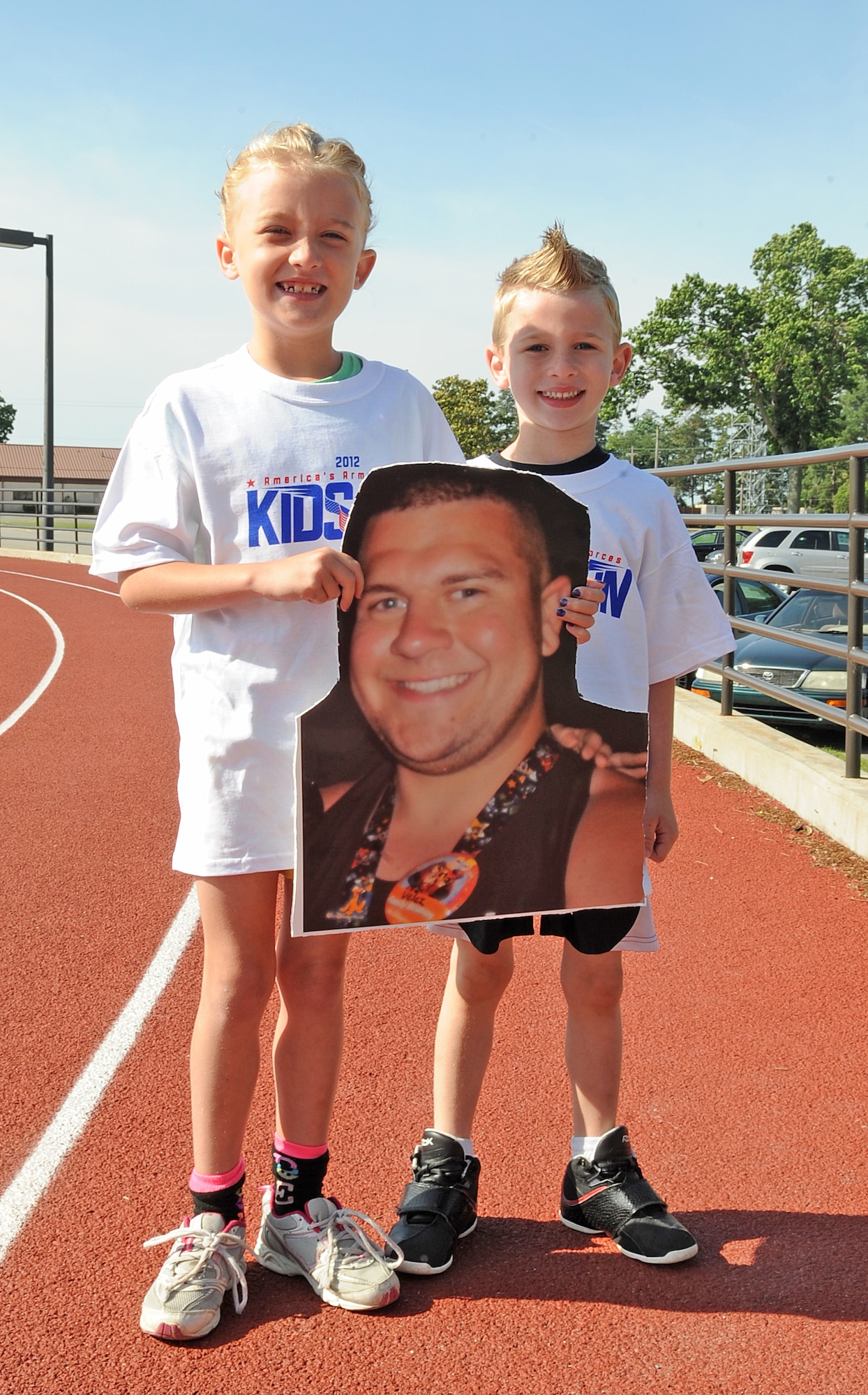 Berkley,7, and Adam, 5, Quaintance smile as they hold a photo of their father U.S. Air Force Senior Airman Tomas Velez-Ojeda before the America’s Armed Forces Kids Run event on Seymour Johnson Air Force Base, N.C., May 19, 2012. The children take the photo of their currently deployed father wherever they go to pretend like he is always with them. Velez-Ojeda is assigned to the 4th Equipment Maintenance Squadron armament flight. Berkley and Adam are natives of Arizona. (U.S. Air Force photo/Airman 1st Class Aubrey Robinson/Released)