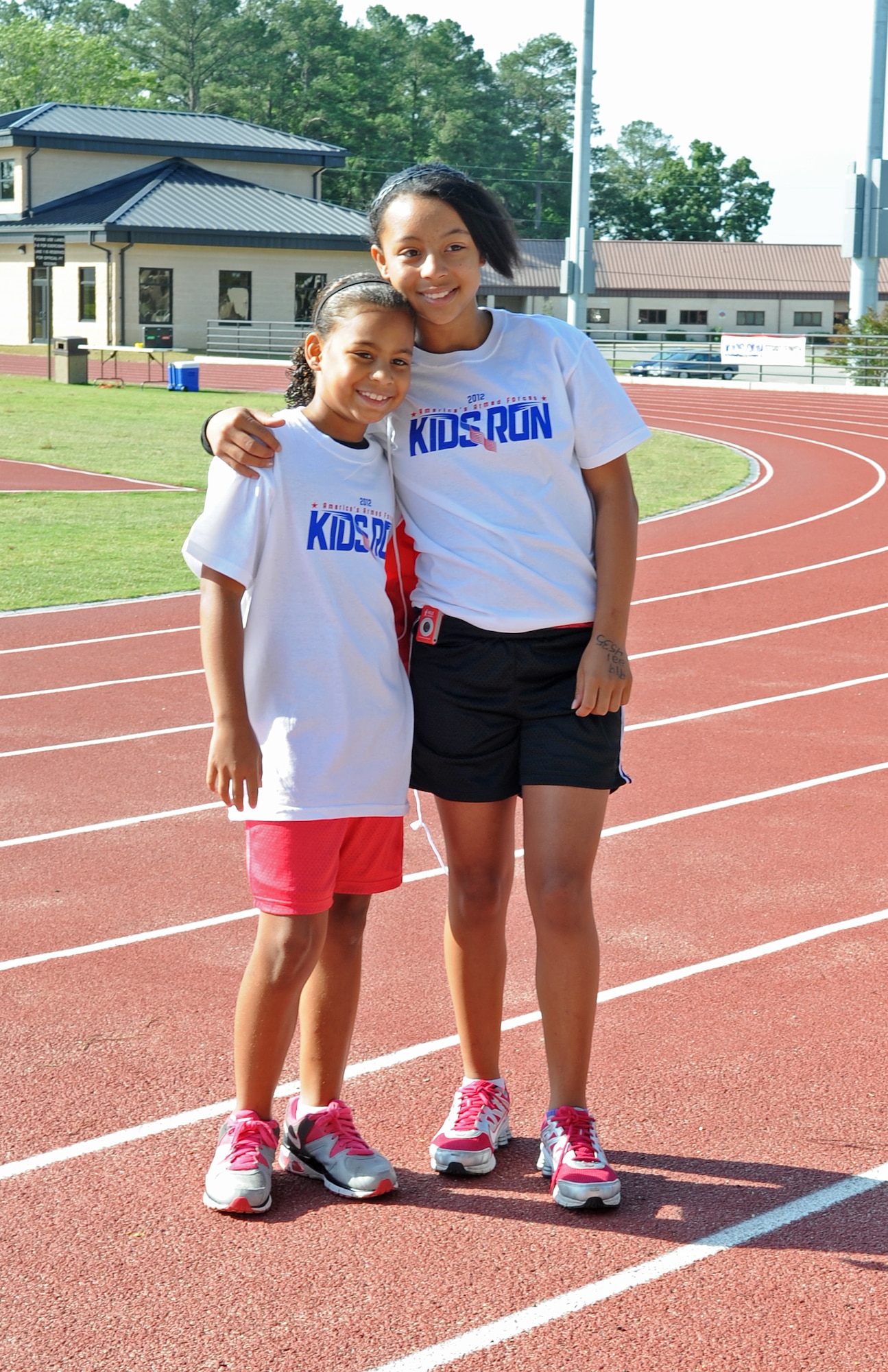 Jada Thomas, 9, and Destiny Waltman, 12, smile for a picture while waiting for a race to begin during the America’s Armed Forces Kids Run event on Seymour Johnson Air Force Base, N.C., May 19, 2012. The children participated in the half and one-mile races. Jada and Destiny are the daughters of U.S. Air Force Staff Sgt. Andrew Thomas, 4th Equipment Maintenance Squadron aircraft structural maintenance craftsman. Jada is a native of Goldsboro, N.C., and Destiny hails from Panama City, Fla. (U.S. Air Force photo/Airman 1st Class Aubrey Robinson/Released)