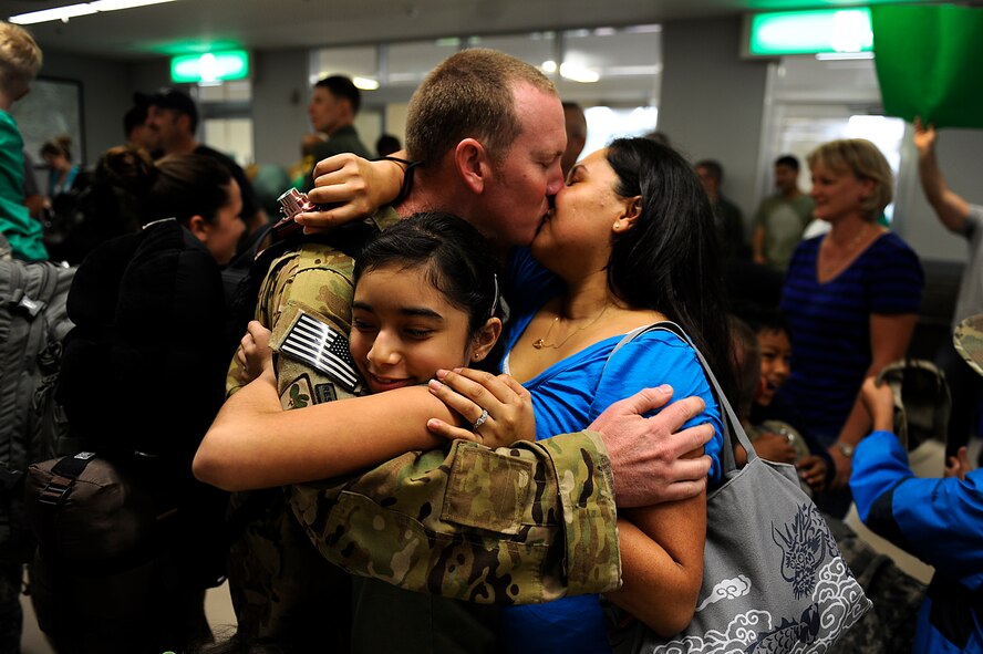 U.S. Air Force Staff Sgt. Mark Smith, 33rd Rescue Squadron flight engineer, kisses his wife, Jessica, and hugs his daughter, Victoria, during the 33rd RQS and 718th Aircraft Maintenance Squadron's homecoming at the Air Mobility Command terminal on Kadena Air Base, Japan, May 20, 2012. Roughly 50 Airmen from the two squadrons returned to Kadena May 20 after a four-month deployment to Afghanistan. (U.S. Air Force photo/Airman 1st Class Maeson L. Elleman)
