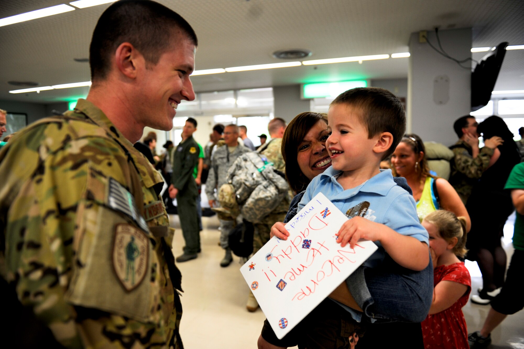 U.S. Air Force 1st Lt. Kevin Rynbrandt (left), 33rd Rescue Squadron HH-60 Pave Hawk helicopter pilot, greets his wife, Katie, and son, Drew, during the 33rd RQS and 718th Aircraft Maintenance Squadron's homecoming in the Air Mobility Command terminal at Kadena Air Base, Japan, May 20, 2012. Family and friends wielding "Welcome Home" signs greeted the redeployers in the terminal May 20 after their four-month deployment to Afghanistan. (U.S. Air Force photo/Airman 1st Class Maeson L. Elleman)