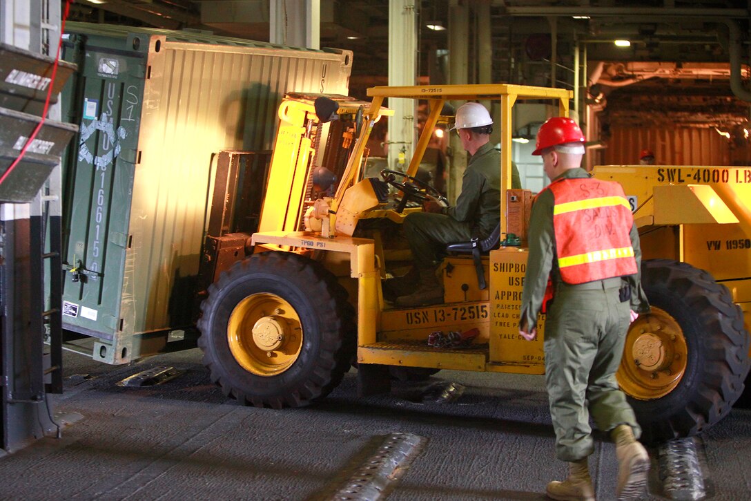 A Marine with the USS Peleliu’s Combat Cargo loads a metal container into the ship during the embarkation period, here, May 23. Marines and sailors with the 15th MEU and Amphibious Squadron 3 began PHIBRON-MEU Interoperability, their first at-sea period as a full Marine Air-Ground Task Force, May 31. Before the training started, the 15th MEU’s embarkation specialists and landing support specialists with the Port Operations Group were tasked with loading the USS Peleliu and USS Rushmore with vehicles, equipment and cargo.