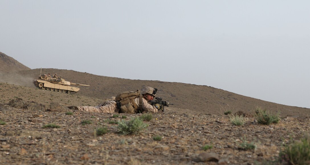 A Marine with Charlie Company, 1st Battalion, 8th Marine Regiment lays in the prone while an M1A1 Abrams tank moves in the background, April 18. The Marines of Charlie Company and Alpha Company, 1st Tank Battalion took part in a month-long clearing operation in the Geston valley of the northern Helmand province.