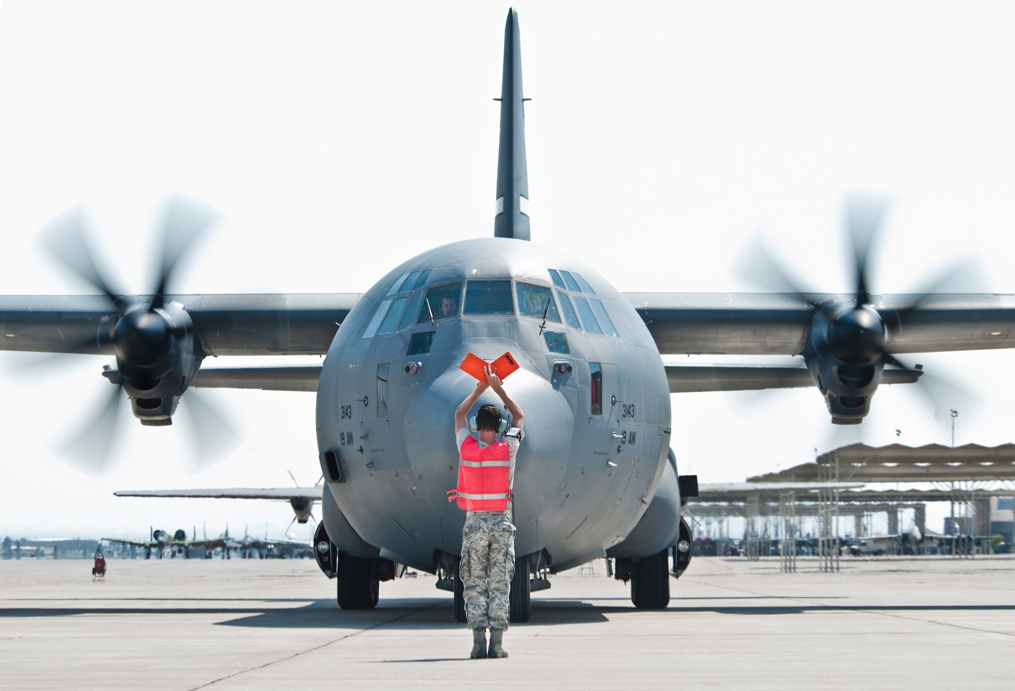 A U.S. Air Force crew chief marshals a C-130J Hercules aircraft assigned to the 19th Airlift Wing, Little Rock Air Force Base, Ark., on the Nellis flight line after the crew participated in the Mobility Air Forces Exercise May 23, 2012 over the Nevada Test and Training Range. More than 25 C-130 aircraft assembled in aerial formations over the Nevada Test and Training Range to conduct air and ground operations as part of the biannual U.S. Air Force Weapons School Mobility Air Forces Exercise.  (U.S. Air Force photo by Lawrence Crespo)