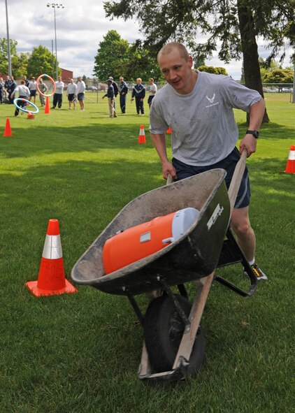 Airman 1st Class Mikhal Scheglov, 92nd Comptroller Squadron military pay technician, pushes a wheelbarrow through an obstacle course during the 101 Critical Days of Summer kickoff event at Fairchild Air Force Base, Wash., May 24, 2012. The Commander’s Cup Challenge featured other events including a 1.6 mile run, Tug-o-War and fire truck pull. (U.S. Air Force photo by Senior Airman Benjamin Stratton/Released)  