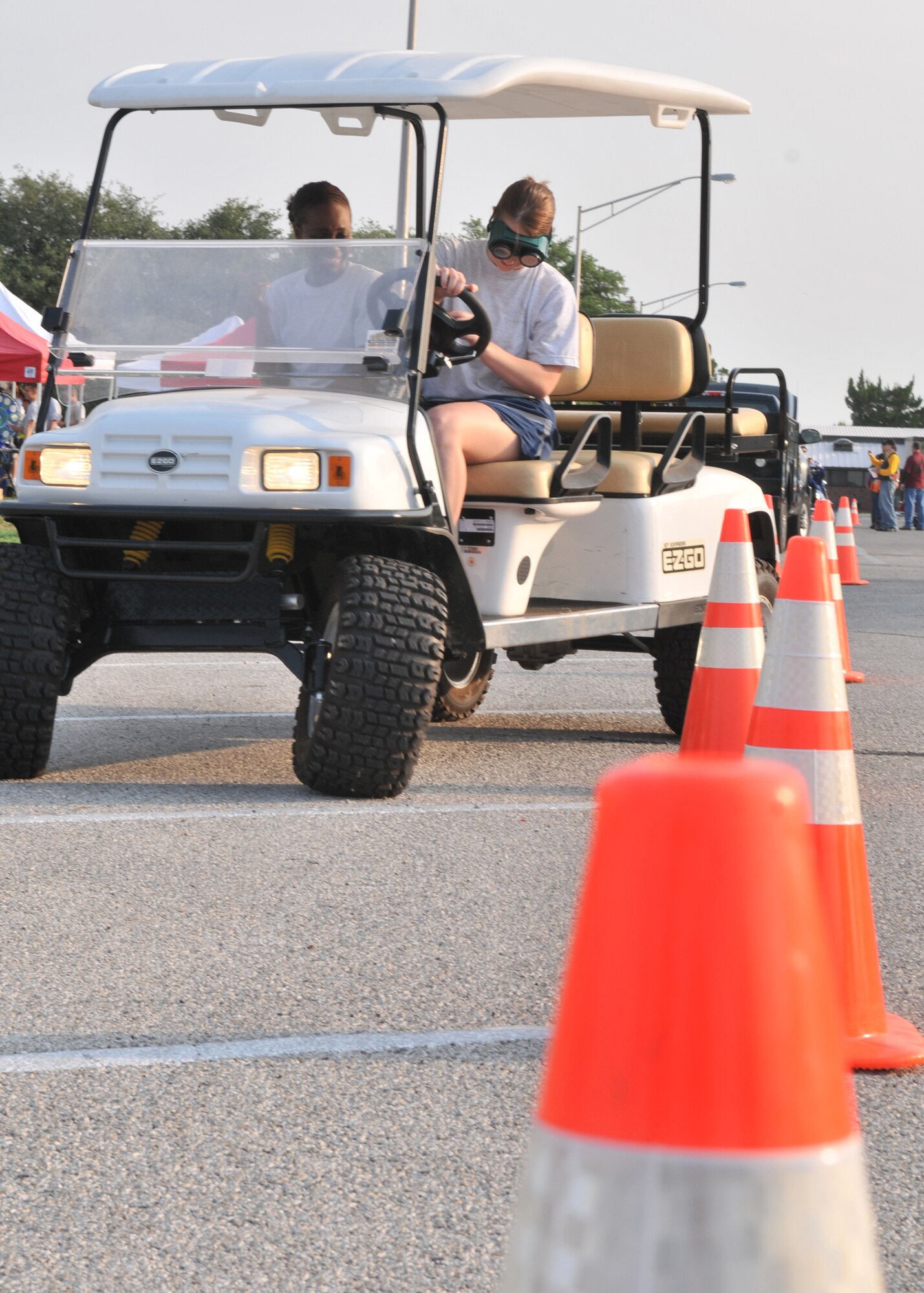 GOODFELLOW AIR FORCE BASE, Texas – Airman Sage Bradford, 17th Medical Squadron member attempts to navigate around cones while donning “impairment” goggles, as Tech. Sgt. Curtrell Gibson, 17th MDG member spots for her. The golf cart and goggles allow participants to experience driving under the influence, and was one of many events during Safety and Sports Day which focused on safety during the 101 days of summer. (U.S. Air Force photo/ Staff Sgt. Tong Duong)