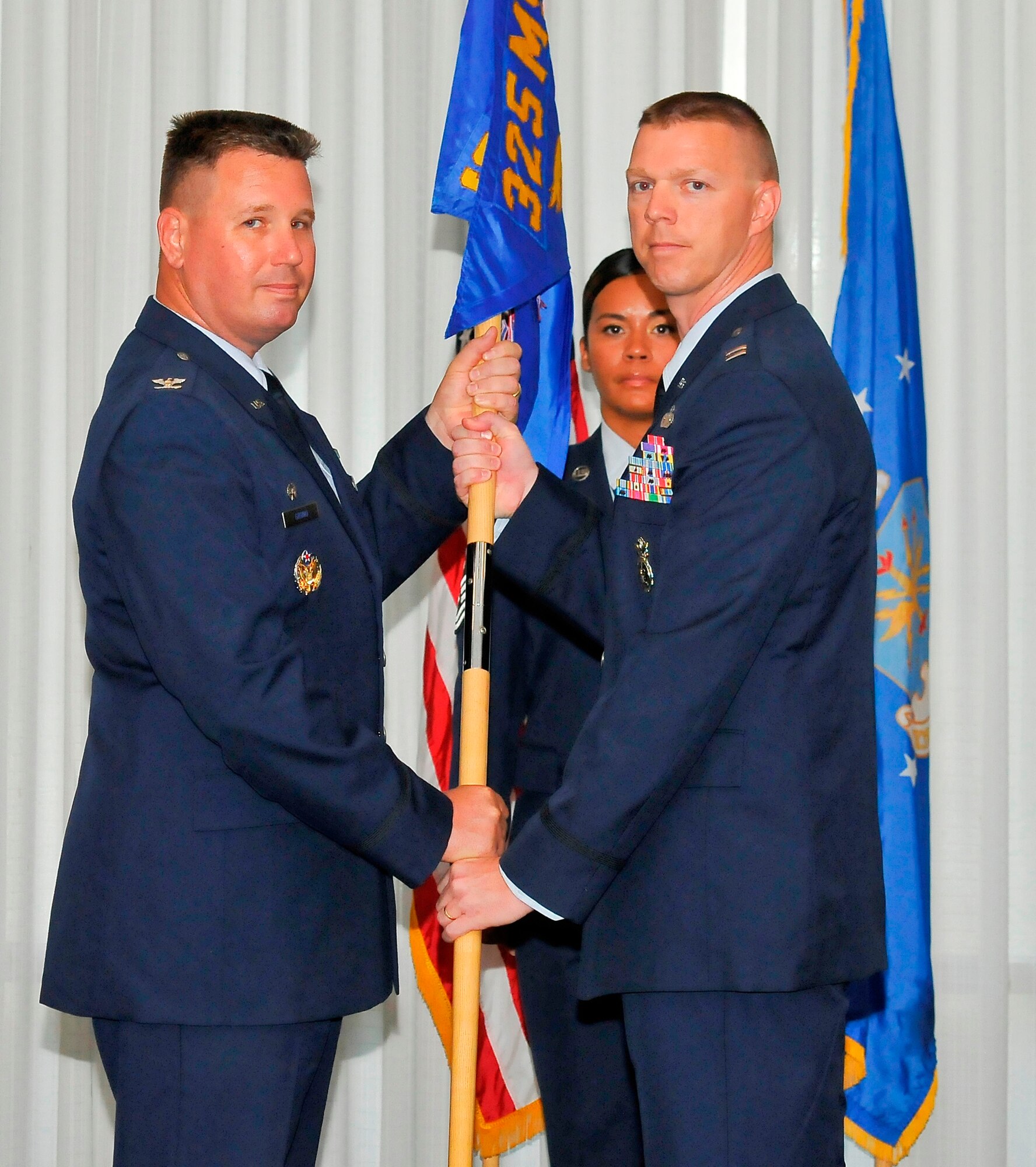 Colonel William Grund, 325th Mission Support Group commander, passes the 325th Security Forces Squadron guidon to Captain Anthony McCarty, 325th SFS commander, as Master Sgt. Jessica Rashid, 325th SFS first sergeant, looks on during the change of command ceremony, May 24. Captain McCarty arrived from Joint Base Langley-Eustis, Va. where he served as the strategic communications and speech writer. (U.S. Air Force photo by Christopher Cokeing)