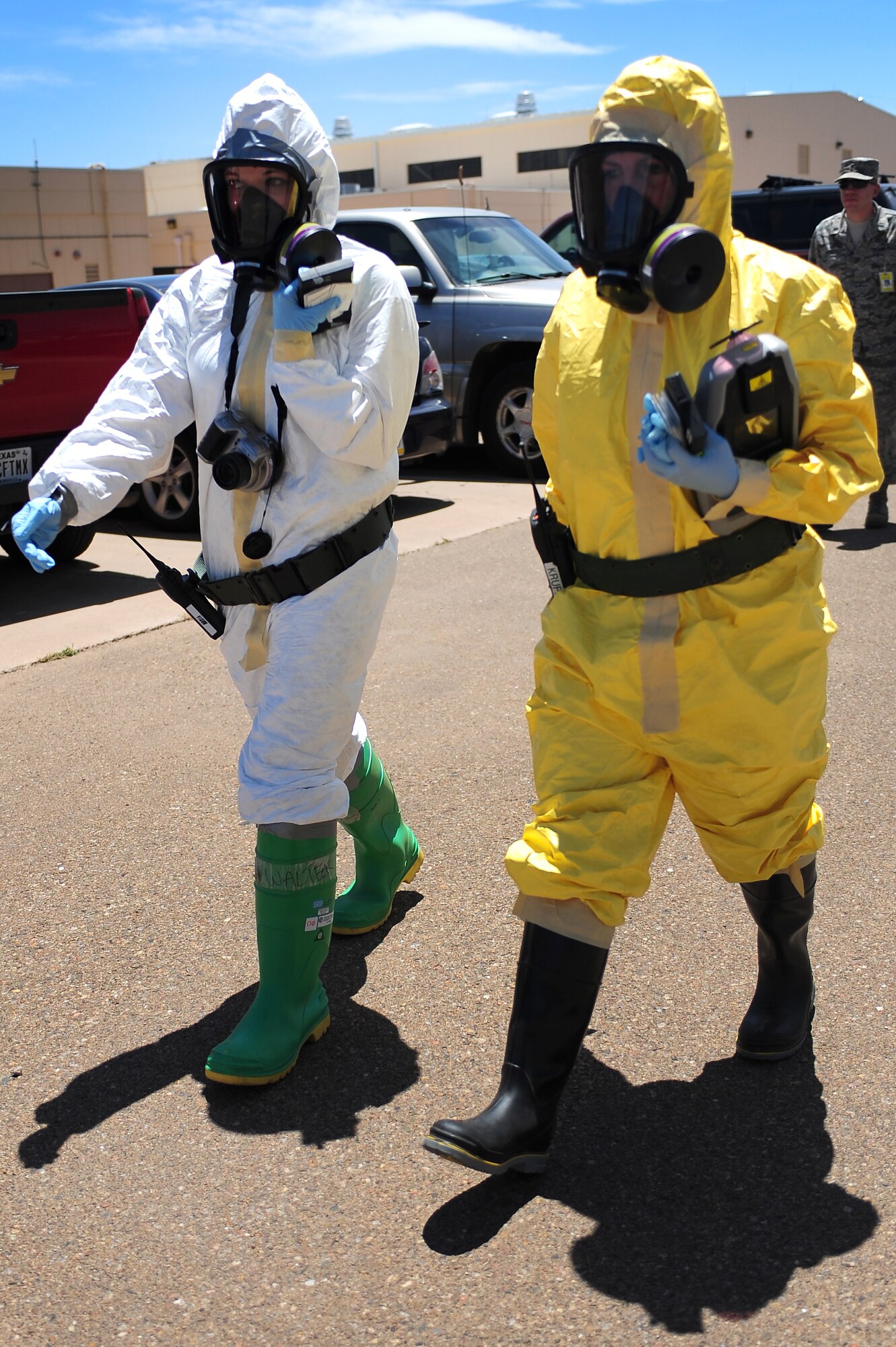 U.S. Air Force Staff Sgt. Rachael Walter, 27th Special Operations Aerospace Medical Squadron, and Senior Airman Brittany Krupa, 27th Special Operations Civil Engineer Squadron, walk toward a potentially contaminated area during a base-wide exercise at Cannon Air Force Base, N.M., May 23, 2012. Once inside, the team conducted tests on a substance leak from a simulated suspicious package. (U.S. Air Force photo by Airman 1st Class Eboni Reece)