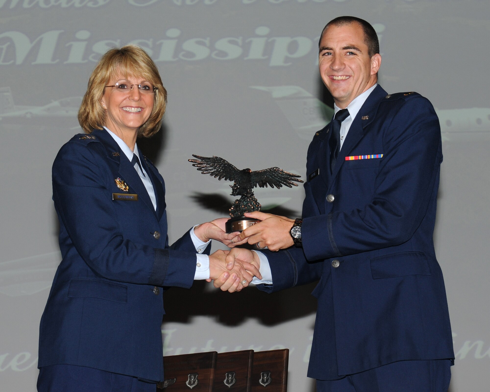 Maj. Gen. Maggie Woodward, acting Director, Operational Planning, Policy and Strategy, Deputy Chief of Staff, Operations, Plans and Requirements, Headquarters U.S. Air Force, Washington, D.C. presents student 2nd Lt. Joel Loftus with the Order of Daedalians Air Education and Training Command Commander’s Trophy during the Specialized Undergraduate Pilot Training class 12-09 graduation.  Maj. Gen. Woodward and her husband, retired Brig. Gen. Dan Woodward, were the first dual graduation speakers in the history of Columbus Air Force Base.