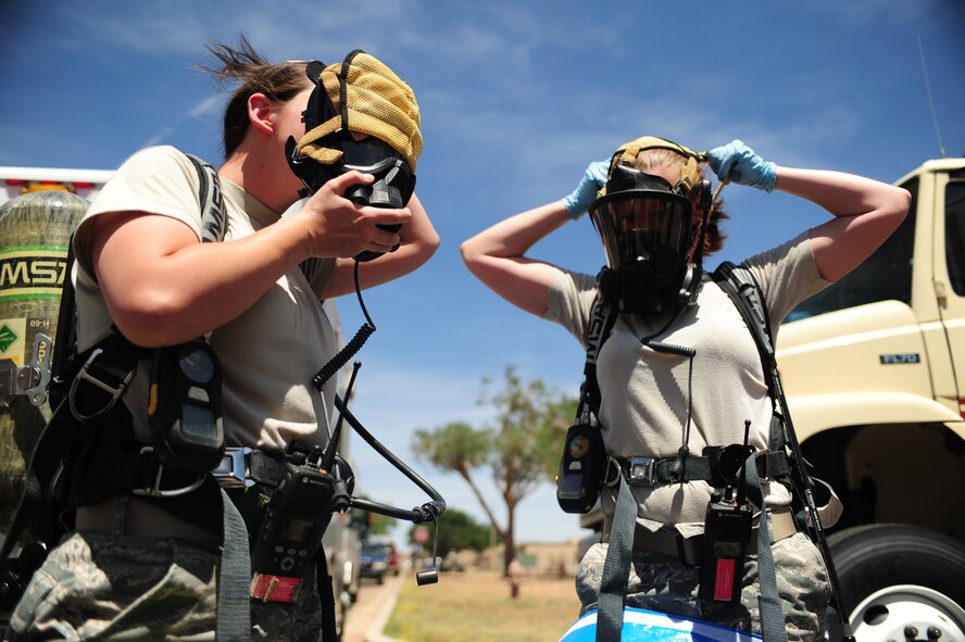 U.S. Air Force Senior Airman Renee Malsom, 27th Special Operations Civil Engineer Squadron emergency management, and Staff Sgt. Tara Sheaib, 27th Special Operations Aerospace Medicine Squadron bioenvironmental engineer technician, put on their gas masks during a base-wide exercise at Cannon Air Force Base, N.M., May 23, 2012. The exercise tested Cannon Air Commandos' abilities to respond to potential real-life incidents. (U.S. Air Force photo by Airman 1st Class Eboni Reece)