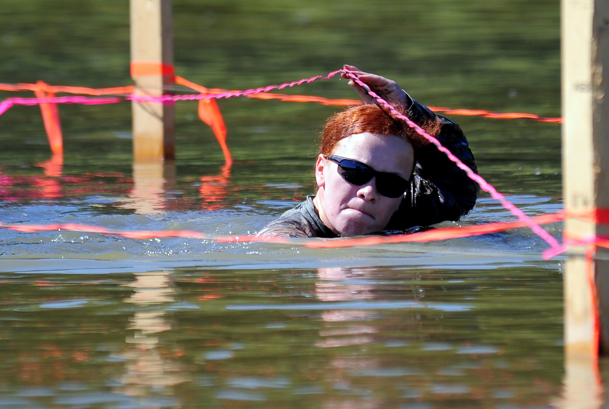U.S. Air Force Staff Sgt. Grace Taylor, 55th Security Forces Squadron, maneuvers her way under cables sitting just inches above the water line as she competes in the "Evasion Challenge" as part of National Police Week May 16 at Offutt Air Force Base, Neb.  The 55th SFS set up a series of obstacles for the challenge from running in mud, swimming, crawling through sand and finishing off with hurdling obstacles.  (U.S. Air Force photo by Josh Plueger)