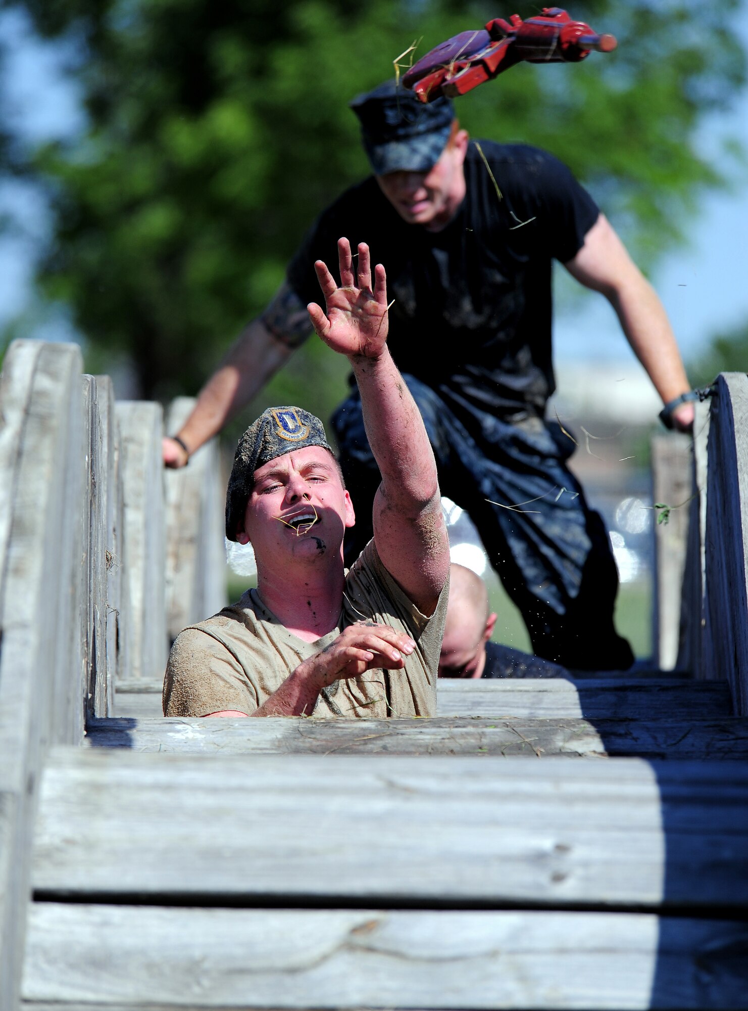 U.S. Air Force 2nd Lt. Erik Olson, 55th Security Forces Squadron, tosses a dummy M16 rifle over wooden cable spindles as he and his team work together to finish the "Evasion Challenge" obstacle course as part of National Police Week May 16 at Offutt Air Force Base, Neb.  The Evasion Challenge tested the participants both physically and mentally as they made their way across a gauntlet of challenges through mud, water and sand.  (U.S. Air Force photo by Josh Plueger)