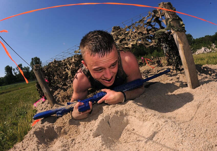 U.S. Air Force Senior Airman James Ray, 55th Security Forces Squadron, crawls through sand, under a camouflage canopy,  as he makes his way through one of several obstacles set up for the "Evasion Challenge" May 16 at Offutt Air Force Base, Neb. Several teams consisting of several military branches competed in the National Police Week challenge arranged by the 55th SFS.  (U.S. Air Force Photo by Josh Plueger)