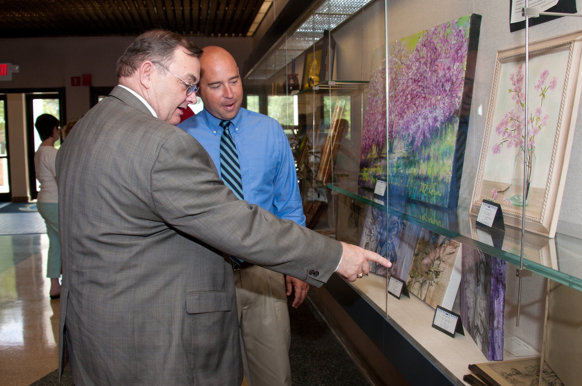Dr. Bruce Murphy (left), vice president for academic affairs at the Air University, and Dr. Frank Luzius, Director, Fairchild Research Information Center, look at artwor during a reception May 17 at the Muir S. Fairchild Research Information Center. The exhibit features artwork from the Capital City Artists.