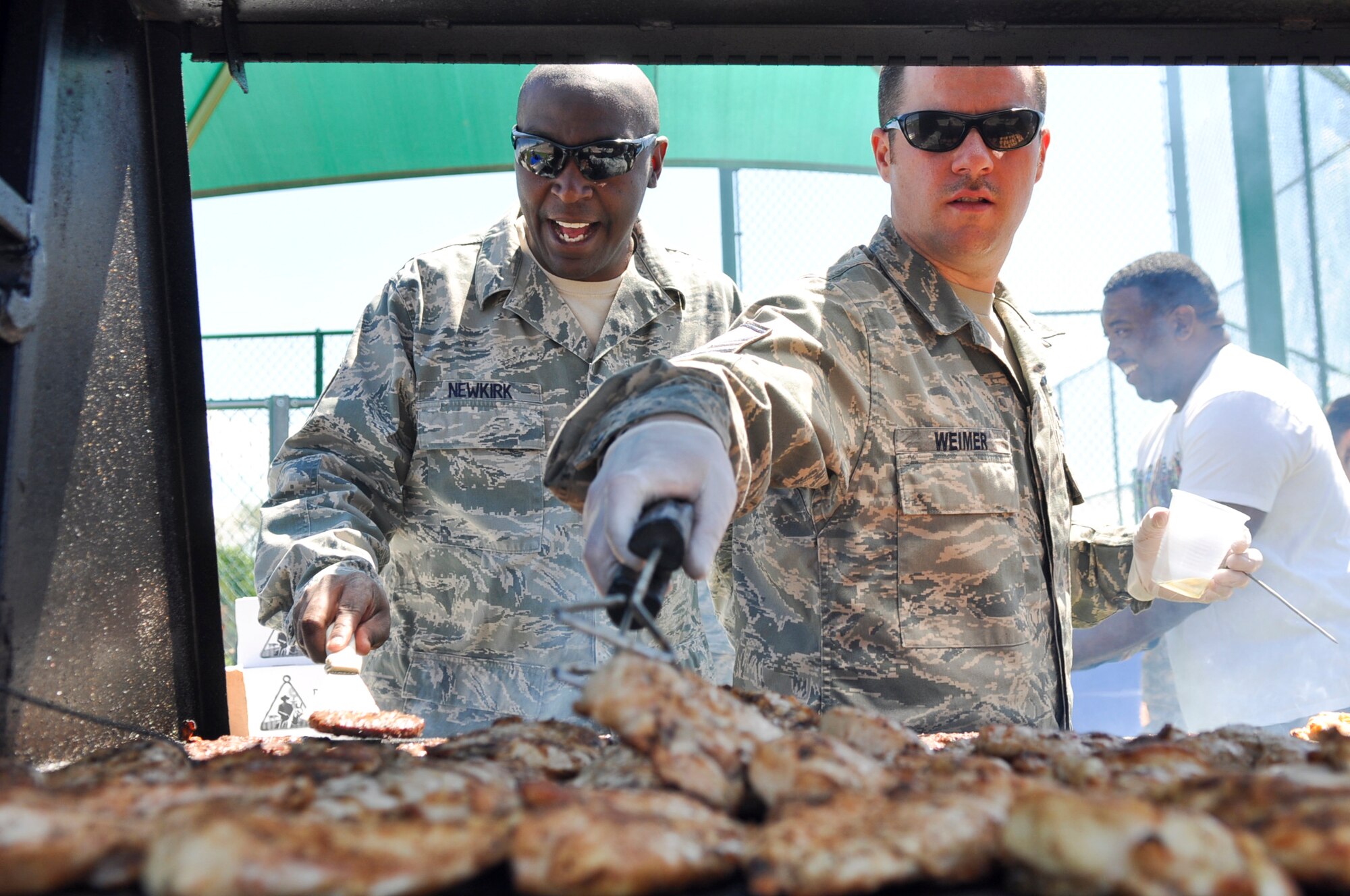 BUCKLEY AIR FORCE BASE, Colo. – Master Sgt. Darnell, left, of the 460th Medical Group, and Master Sgt. Shaun Weimer, of the 460th Space Communications Squadron, flip hamburgers and chicken as they volunteer to cook for those attending Team Buckley’s Post-Operational Readiness Inspection Party May 24, 2012. 