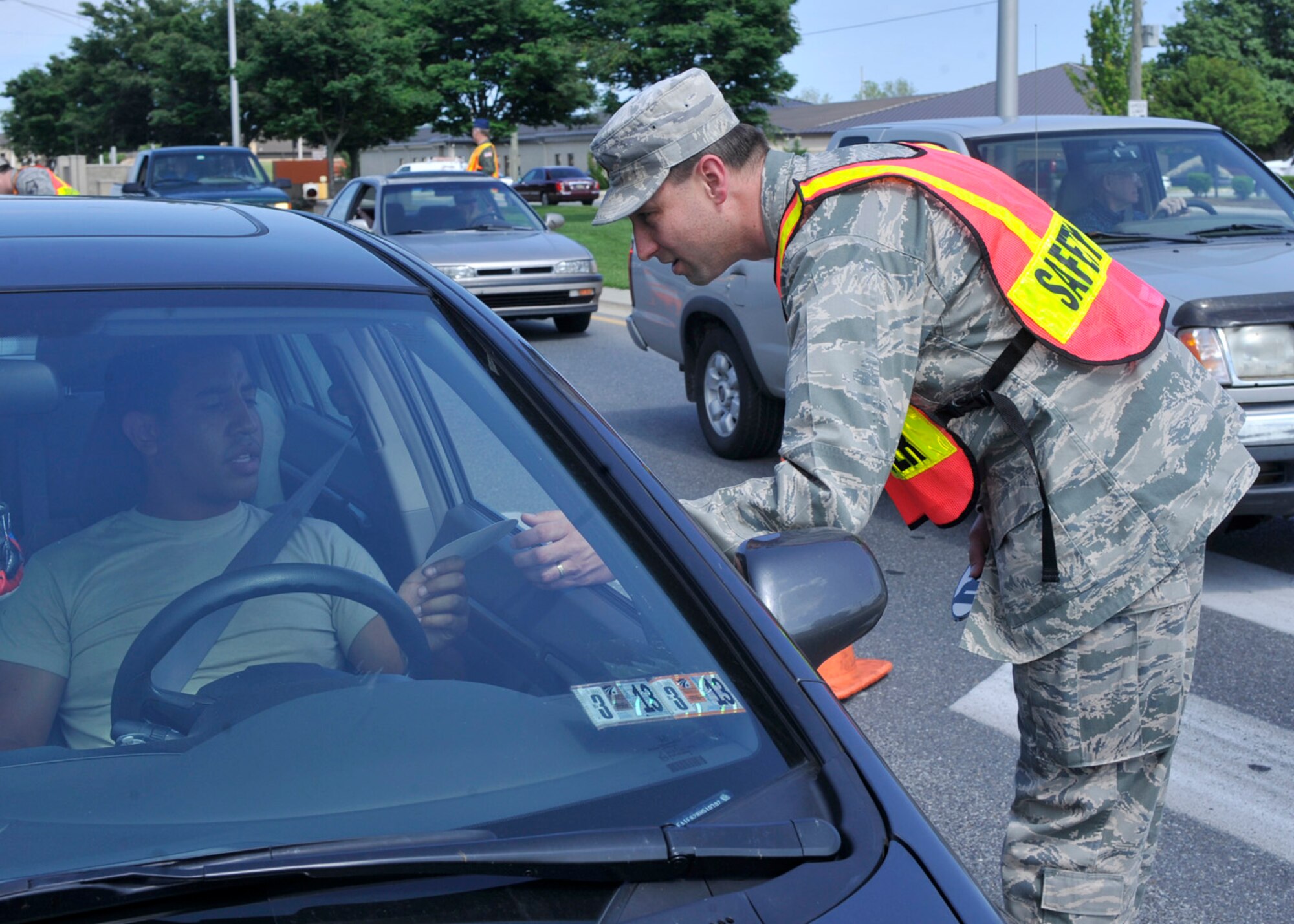 Maj. David Canady, 436th Communications Squadron commander, hands out a "101 Critical Days of Summer" sticker to a driver May 24, 2012, at the main gate on Dover Air Force Base, Del. Memorial Day weekend kicks off the 101 Critical Days of Summer for the Air Force. (U.S. Air Force photo by Tech. Sgt. Chuck Walker)