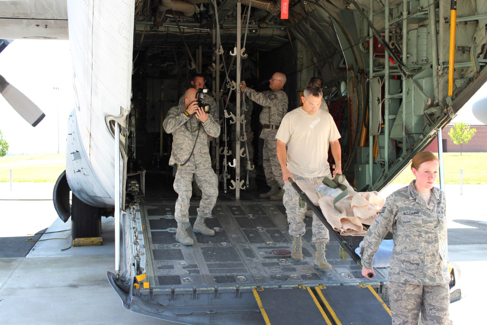 Technical Sgt. David Kujawa takes a photo as a group of medical specialist Airmen take a stretcher off a C-130 Hercules during a simulated medical evacuation during a training exercise at the Alpena Combat Readiness Training Center, Mich., May 24, 2012. During the Emergency Medical Training exercise, medical specialists from eight medical groups in seven states gathered to practice responding to a natural disaster. (U.S. Air Force photo by TSgt. Dan Heaton)
