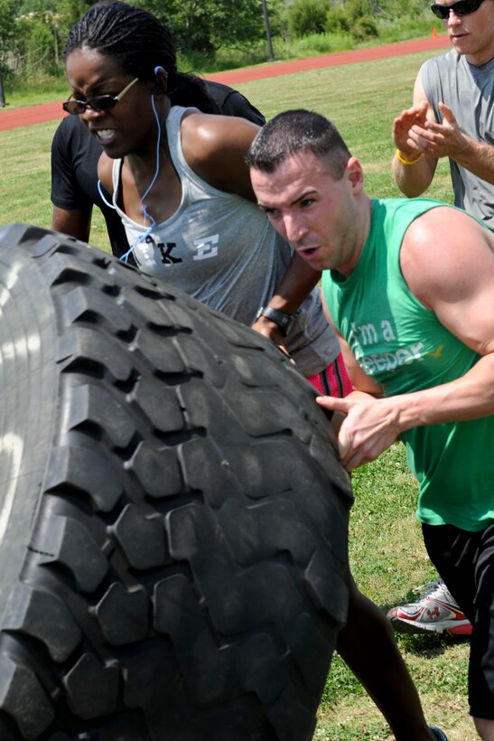 Tiffany White, left, 633rd Force Support Squadron fitness assessment cell examiner, and U.S. Air Force Staff Sgt. Keith Miller 633rd FSS fitness specialist, flip a tire weighing more than 250 pounds during the Squadron Fitness Challenge at the Langley Air Force Base, Va., May 24, 2012. During the event teams competed in several physical challenges for the best time in each event. (U.S. Air Force photo by Senior Airman Wesley Farnsworth/Released)