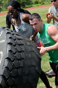 Tiffany White, left, 633rd Force Support Squadron fitness assessment cell examiner, and U.S. Air Force Staff Sgt. Keith Miller 633rd FSS fitness specialist, flip a tire weighing more than 250 pounds during the Squadron Fitness Challenge at the Langley Air Force Base, Va., May 24, 2012. During the event teams competed in several physical challenges for the best time in each event. (U.S. Air Force photo by Senior Airman Wesley Farnsworth/Released)