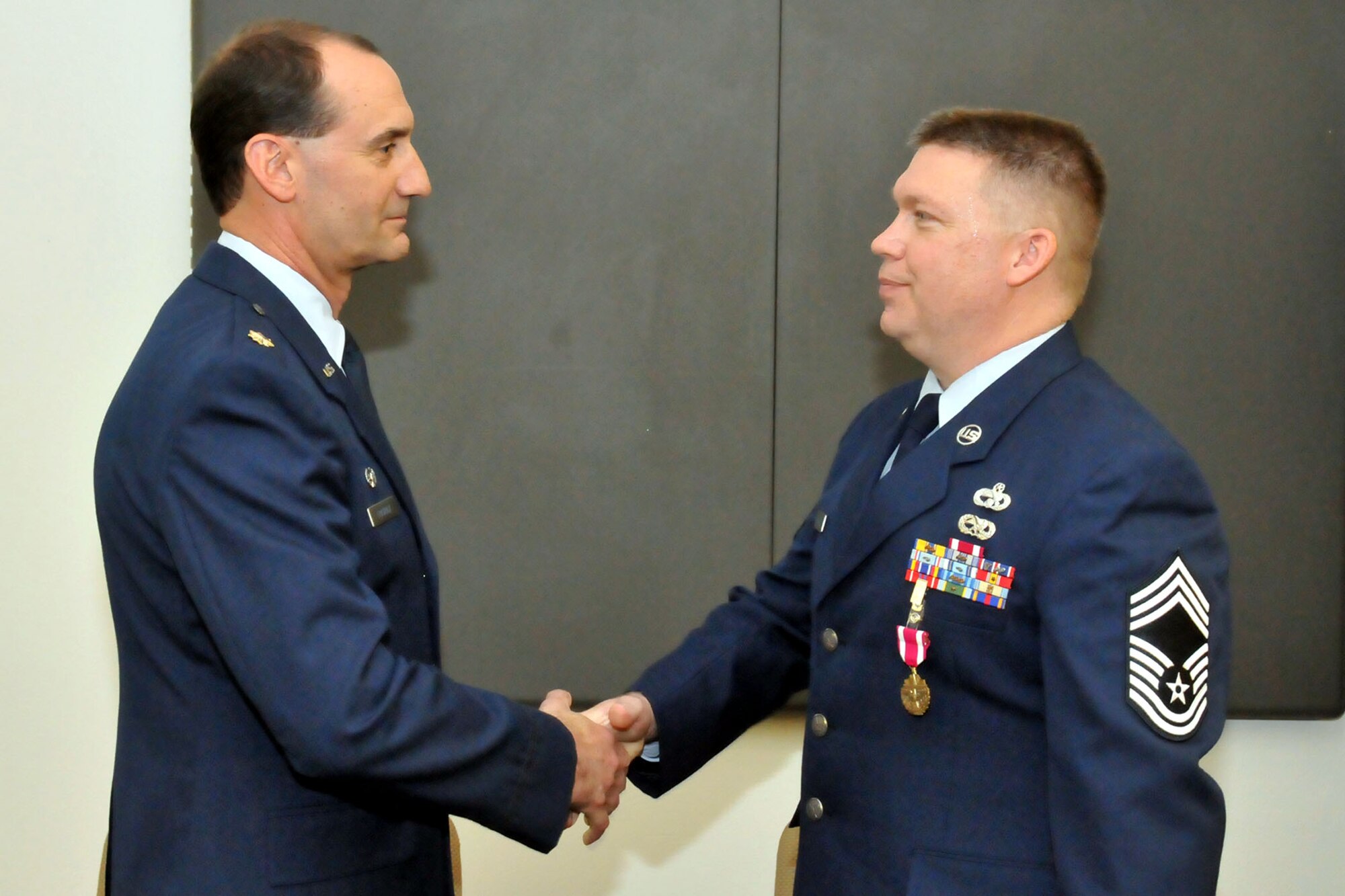 TRAVIS AIR FORCE BASE, Calif. -- Maj Mark Fratrick, 82 APS commander, congratulates Chief Master Sgt Blake Cooke, 82 APS superintendent, upon his retirement here. Chief Cooke spent his entire career in numerous positions within the aerial port community. (U.S. Air Force photo / Master Sgt. Robert Wade)