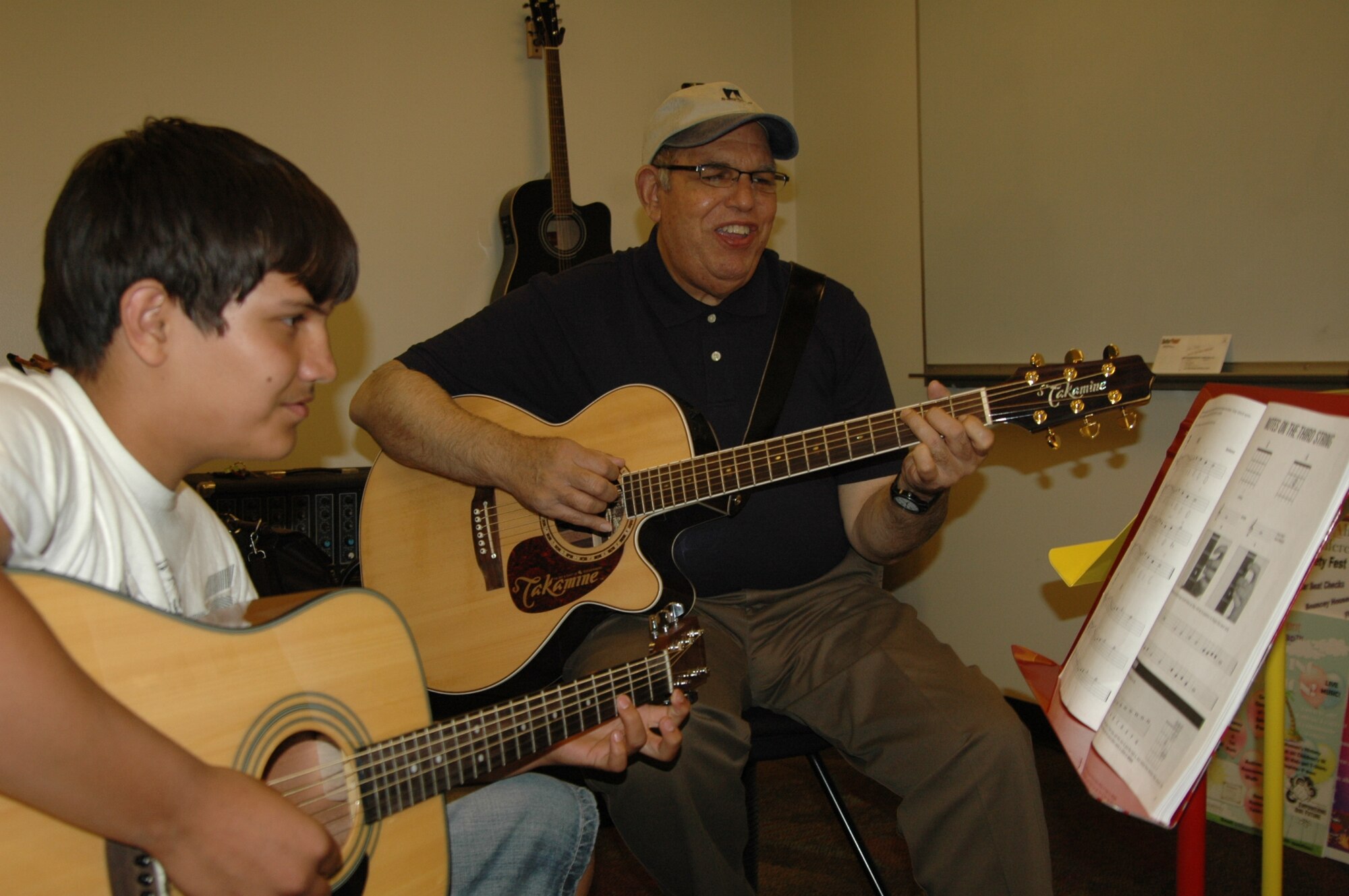 Andrew Plaza, 13, learns how to play guitar May 18 from Rick Rodriquez, Travis Youth Center contractor, at the Youth Center.