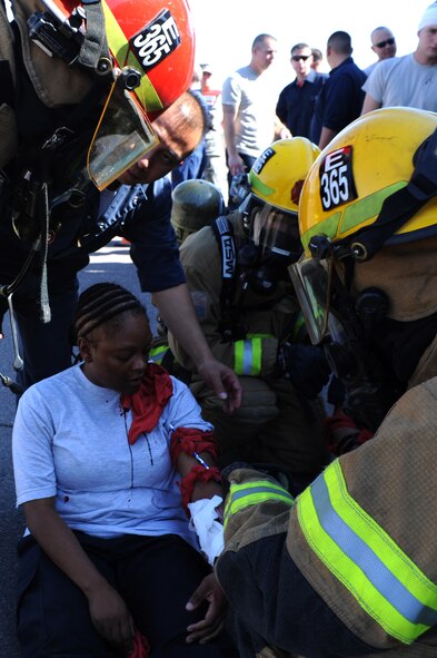Luke Air Force Base firefighters assist Staff Sgt. Sotora Leatham, 56th Logistics Readiness Squadron, during the Crown Talon 12-02 Chemical Biological Radiological Nuclear and Explosive exercise held at the LRS vehicle maintenance compound at Luke Air Force Base May 17. Leathman was treated for simulated injuries that she acquired during the exercise. (U.S. Air Force photo by Airman 1st Class Devante Williams)