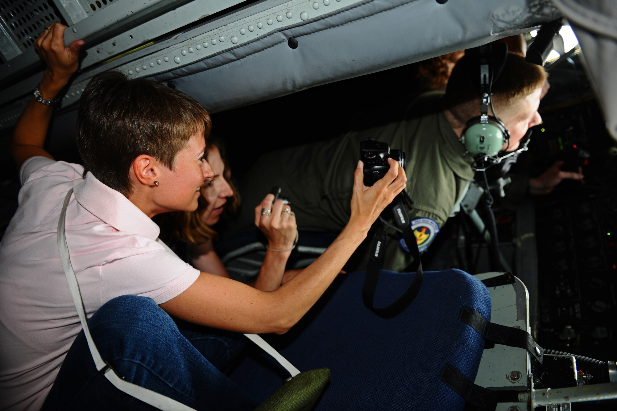 SPANGDAHLEM AIR BASE, Germany – Joy Monroe, left, wife of Tech. Sgt. Andrew Monroe, 52nd Maintenance Group Air Force Smart Operations for the 21st Century representative; and Sara Reilly, center, wife of Capt. Brant Reilly, 480th Fighter Squadron F-16 Fighting Falcon pilot, take photos while watching Staff Sgt. Thomas Vesser, 351st Air Refueling Squadron in-flight refueler, refuel aircraft during an orientation flight for 25 52nd Fighter Wing Airmen and spouses here May 23. The Airmen and spouses flew on a 351st ARS KC-135 stationed out of RAF Mildenhall during an in-flight refueling of 81st and 480th Fighter Squadron aircraft from Spangdahlem AB. The 351st ARS and 52nd FW aircrew train together to enhance their interoperability to perform in-flight refueling missions. (U.S. Air Force photo by Airman 1st Class Matthew B. Fredericks/Released)