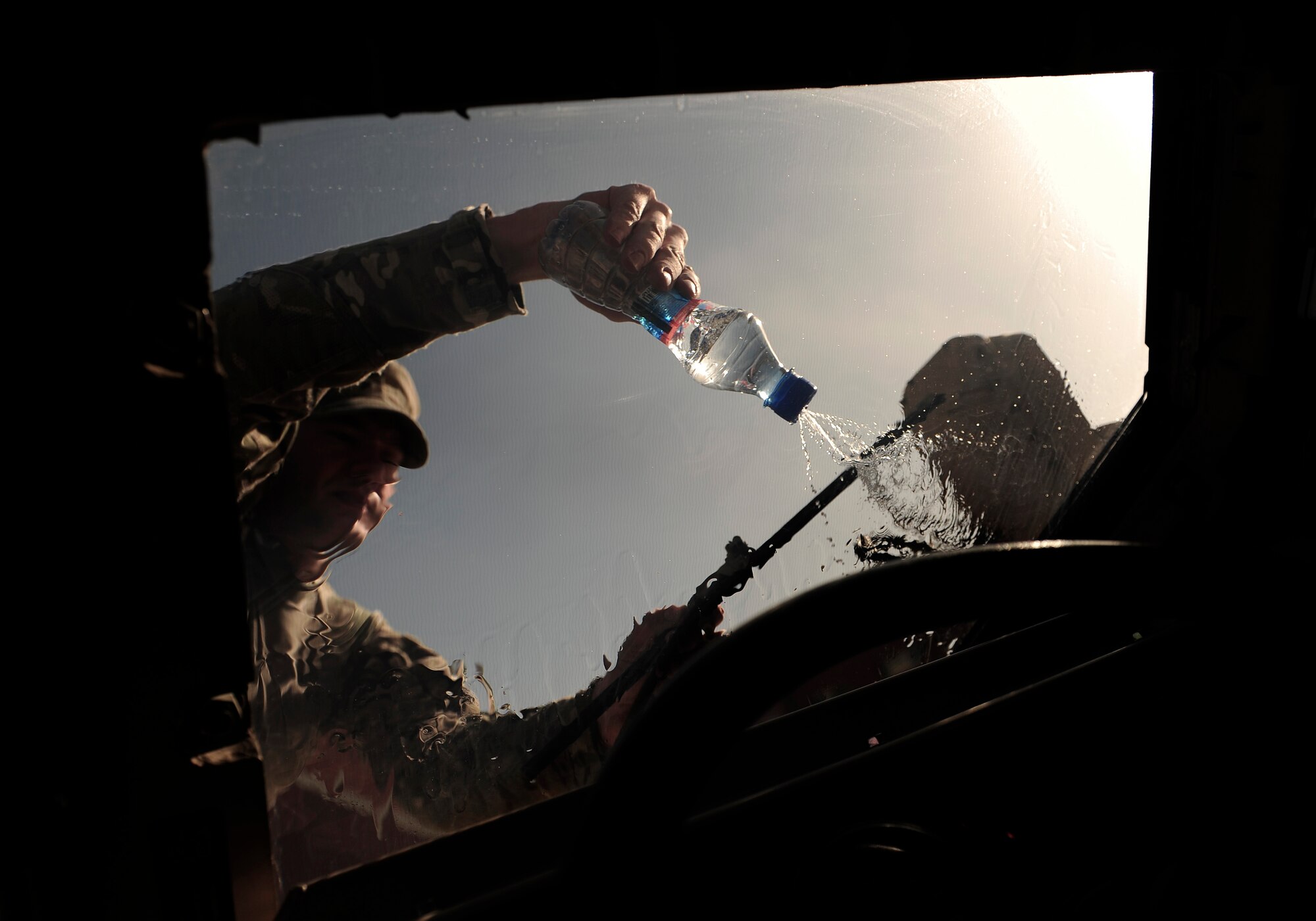 Air Force Security Forces member from the 439th Air Expeditionary Advisor Squadron uses a water bottle to clean a windshield during a mounted and dismounted patrol outside of Kabul, Afghanistan, May 21, 2012. The mission marked the first time AAF security force members led in a reaction force patrol. (U.S. Air Force photo/Staff Sgt. Clay Lancaster)