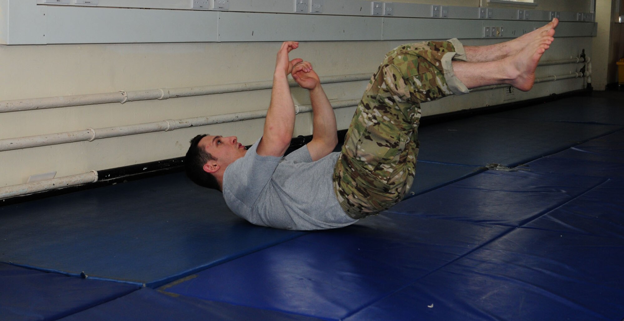 RAF MILDENHALL, England – Staff Sgt. Matt Carlino, 100th Operations Support Squadron Survival, Evasion, Resistance and Escape specialist, demonstrates “eos” – one of many abdominal workouts – as part of the warm-up for the Modern Army Combative Program course May 17, 2012, at RAF Feltwell. Carlino taught the four-day course to five military members from RAF Mildenhall. Students had to perform a variety of exercises to warm up and stretch  their muscles before practicing the moves they had learned one-on-one. As a SERE specialist, he was trained at the Army training MACP school at Fort Benning, Ga. (U.S. Air Force photo/Karen Abeyasekere)