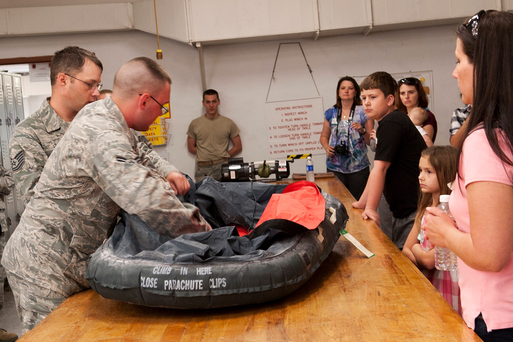 U.S. Air Force Airman First Class Steven Snyder, Aircrew Flight Equipment (AFE) technician, gives a demonstration of an inflatable life raft during Spouse Appreciation Day, Barksdale Air Force Base, La., May 22, 2012. The 2nd Operation Support Squadron hosted the event, giving spouses a tour of the AFE shop. (U.S. Air Force photo by Master Sgt. Greg Steele/Released)