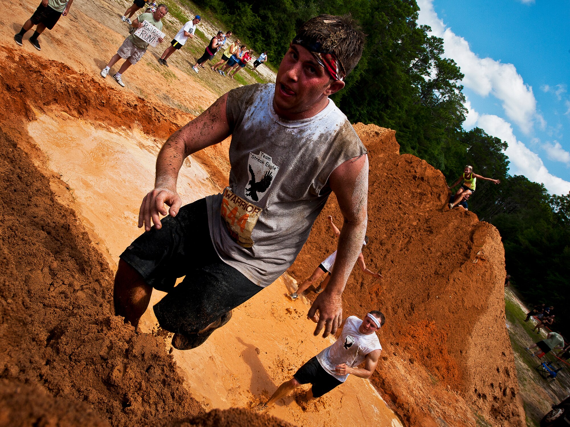 2nd Lt. Thomas Pace, of the 46th Test Wing, scales the last mud hill before the finish of the Emerald Coast MudRun for Orphans in Niceville Fla., May 19. Active duty and reserve service members came out to get dirty in either the morning or afternoon 5K challenges. (U.S. Air Force photo/Samuel King Jr.)